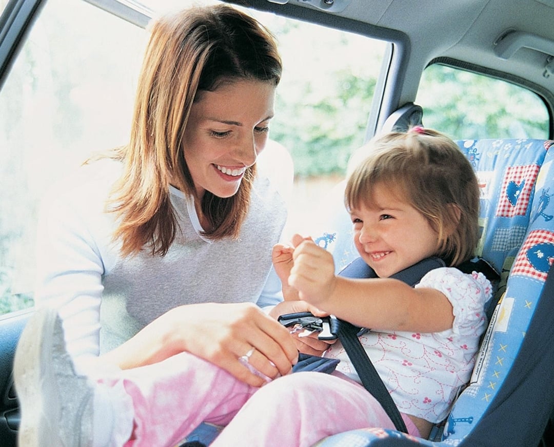 Woman putting kid into car seat